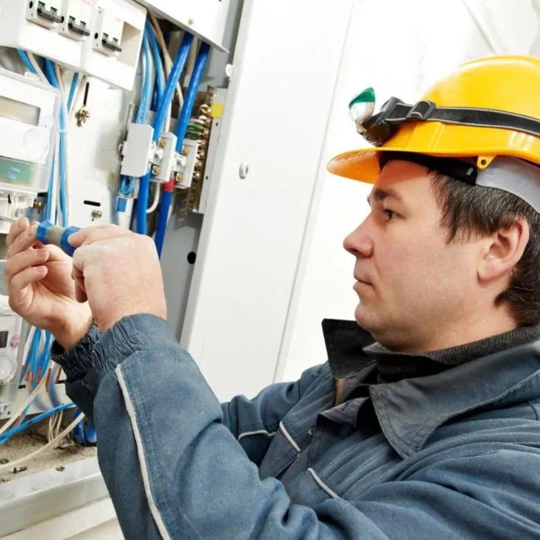 Emergency electrician in a hard hat and headlamp working on an electrical panel