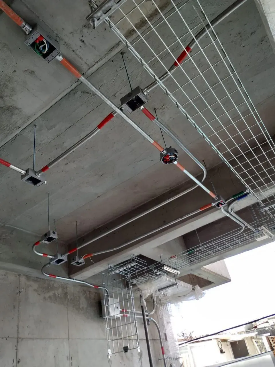 Metal conduit, junction boxes and cable trays installed on the concrete ceiling of a commercial building