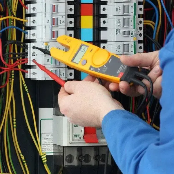 Electrician using a clamp meter to test breakers in a commercial panel