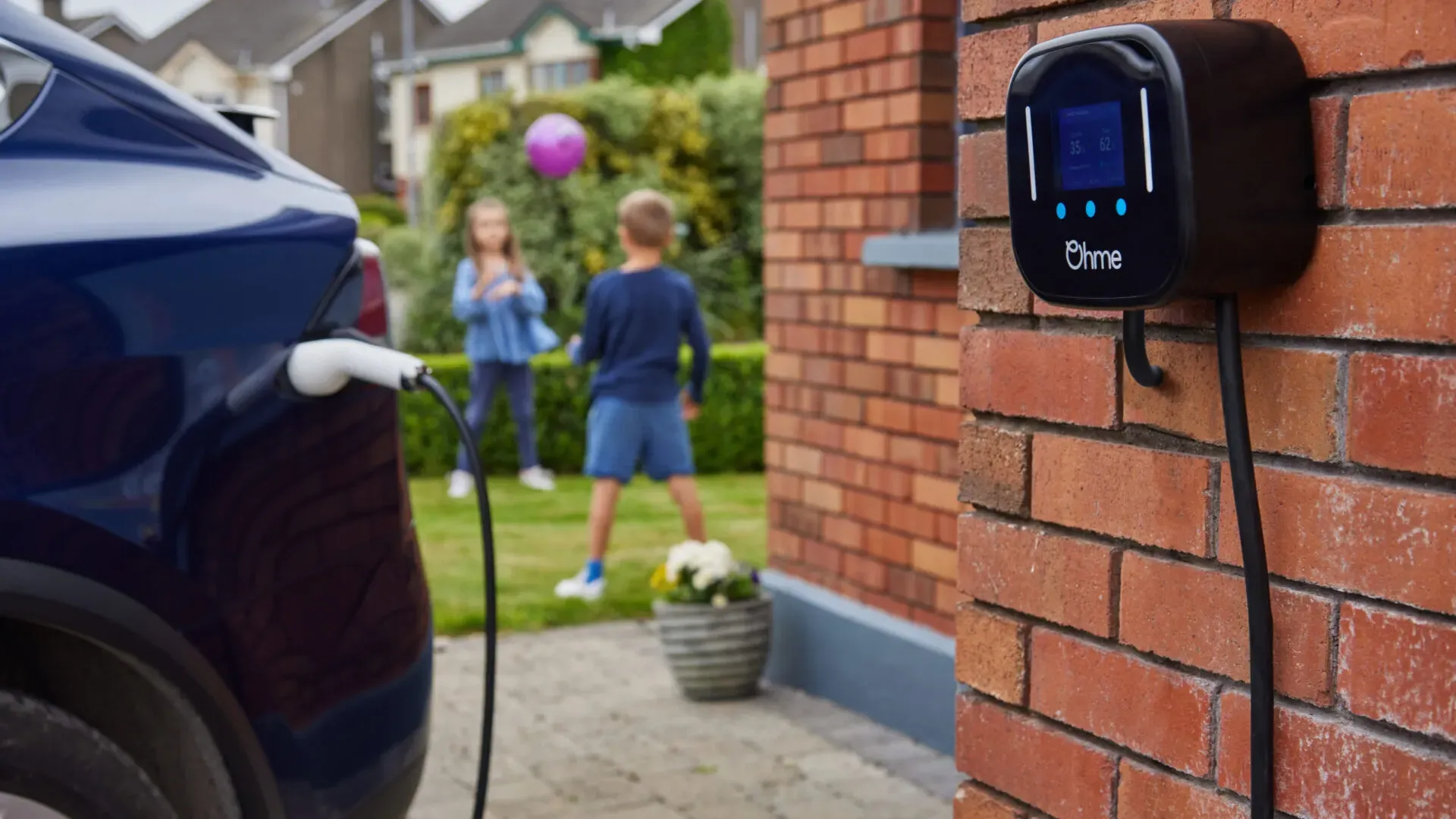 Electric car plugged into a wall mounted Level 2 EV charger on a brick wall
