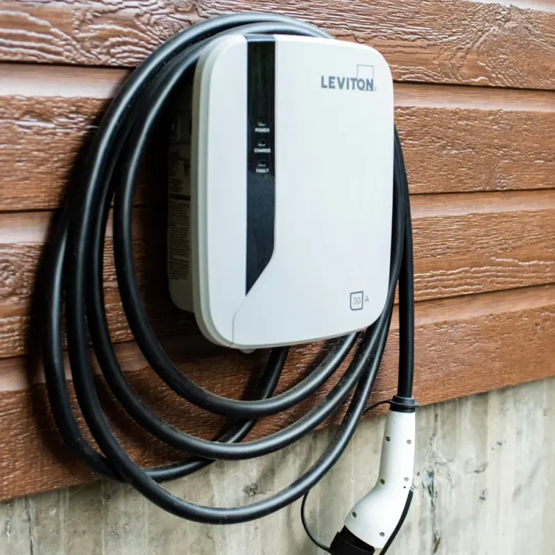 30 amp Level 2 EV charger mounted on an outside wall with its charging cable coiled around it