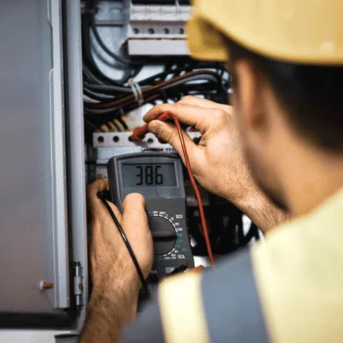 Electrician testing a home electrical panel with a digital multimeter