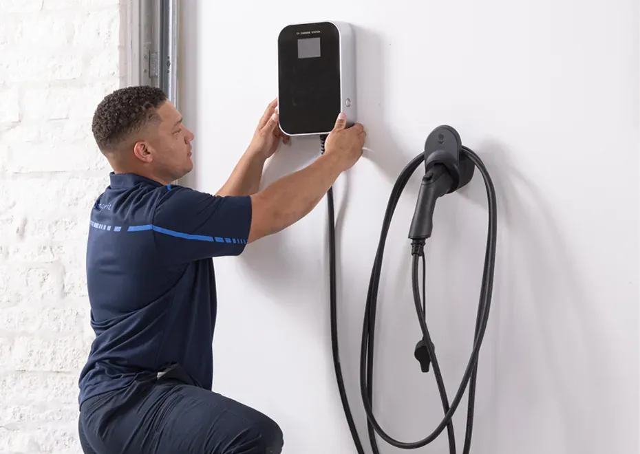 Electrician mounting a Level 2 EV charger on a garage wall