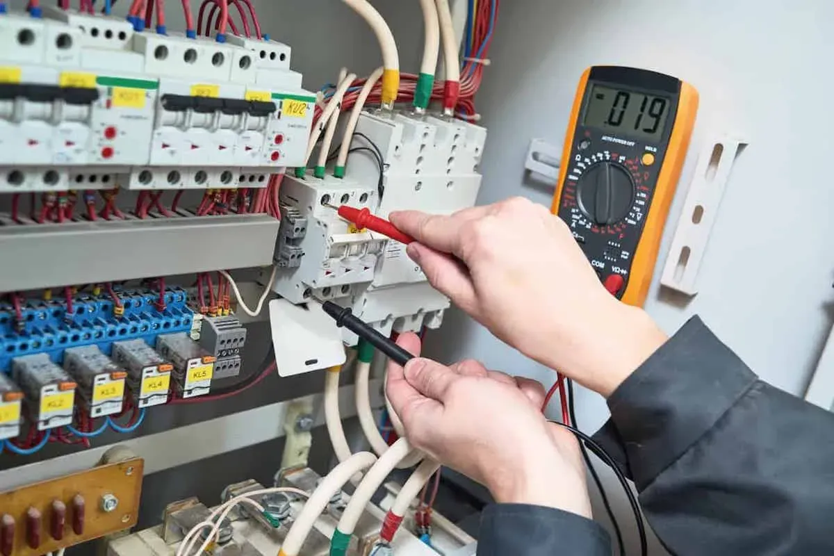 Electrician testing a breaker with multimeter probes inside an open electrical panel