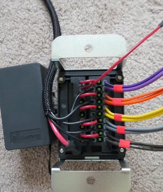 Close-up of a fuse block with color-coded wires connected to each fuse