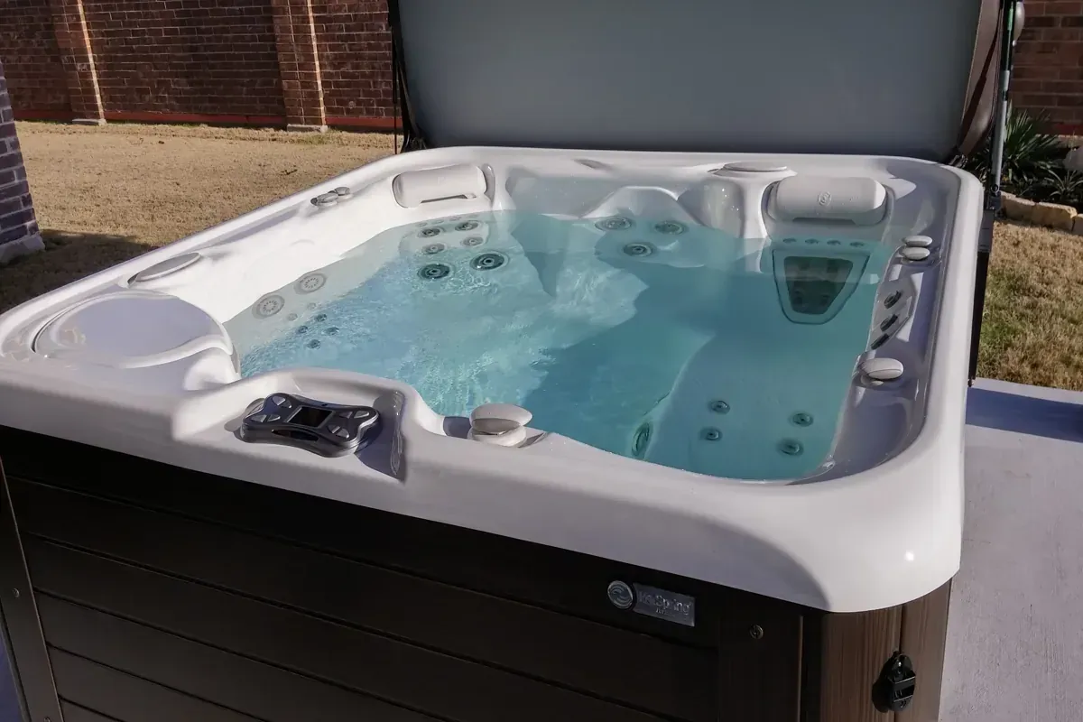 Backyard hot tub with its cover open, the control panel and jets ready to run