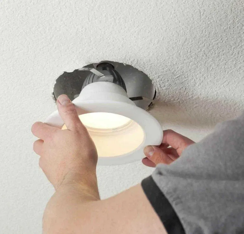 Hands fitting an LED retrofit trim into an existing recessed can light