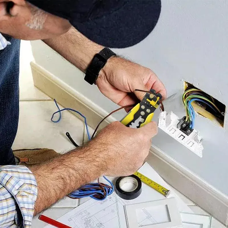 Electrician stripping wire to install a new outlet low on a wall