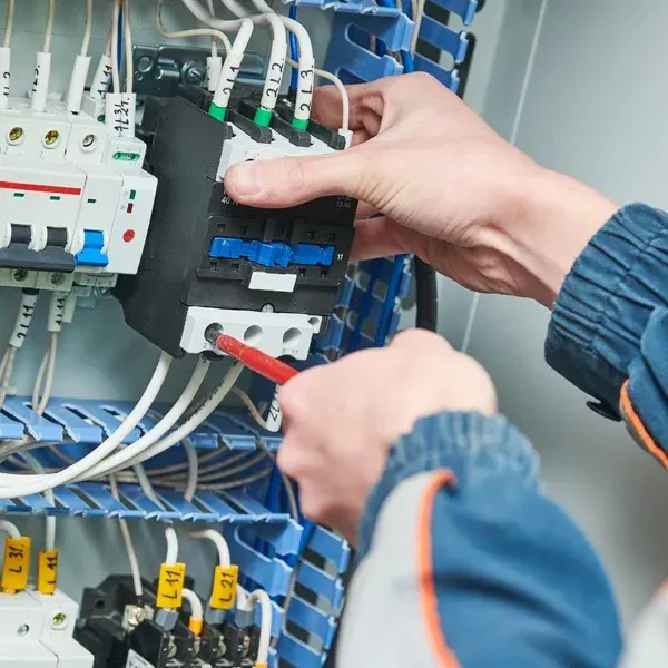 Electrician tightening a connection inside a breaker panel with a screwdriver