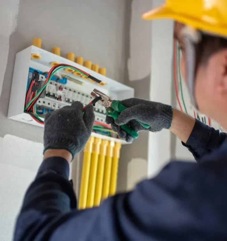 Electrician wearing protective gloves working on wiring inside an electrical panel