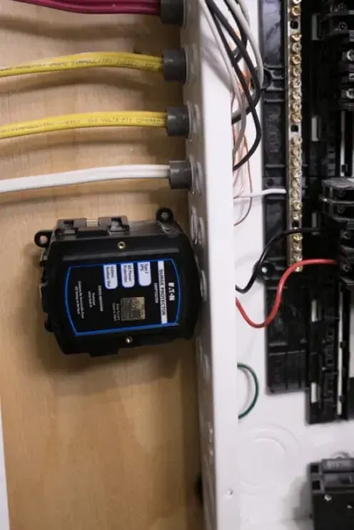 Eaton whole home surge protector mounted beside an open residential breaker panel